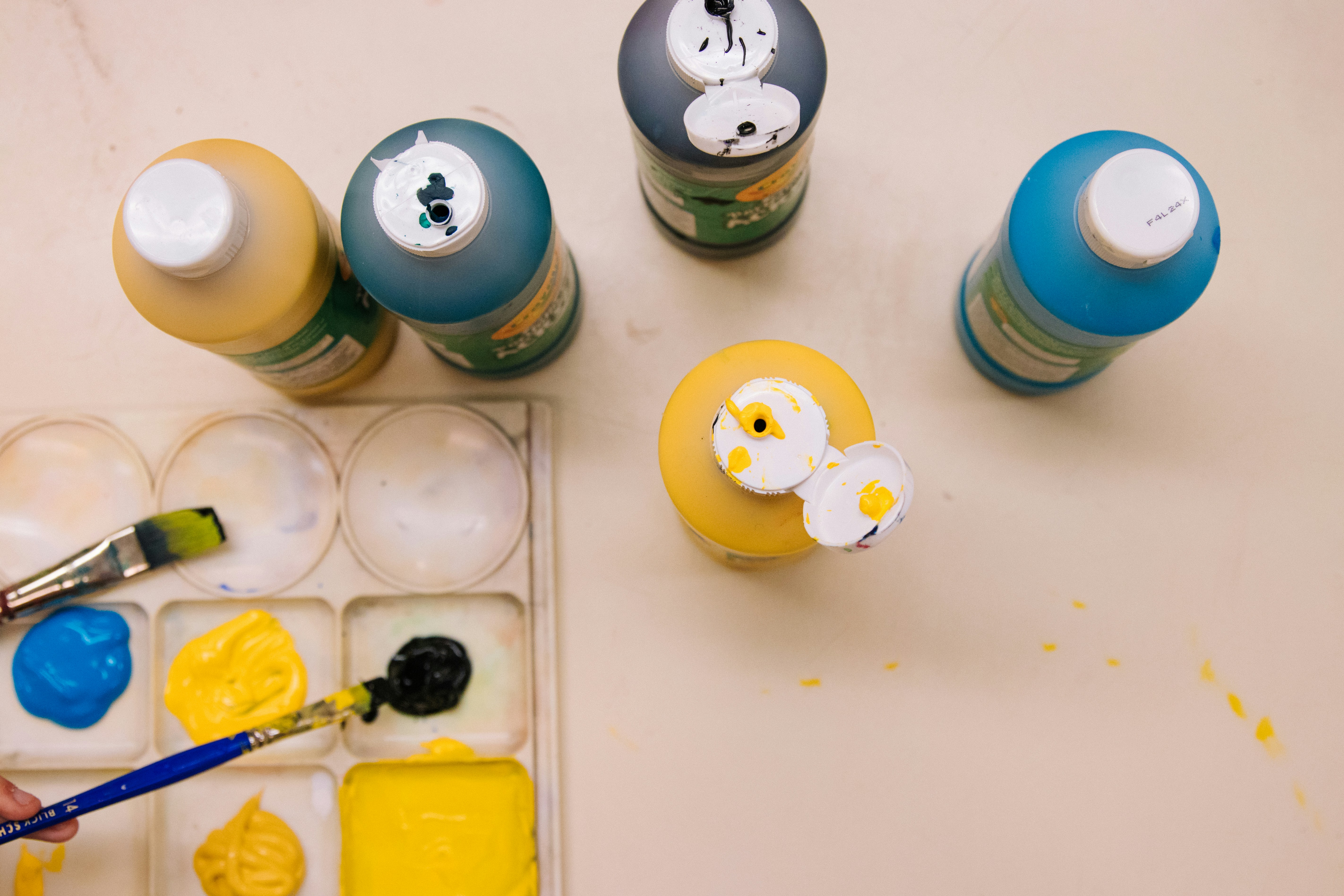 High-angle close-up view of a paint palette and bottles of paint.